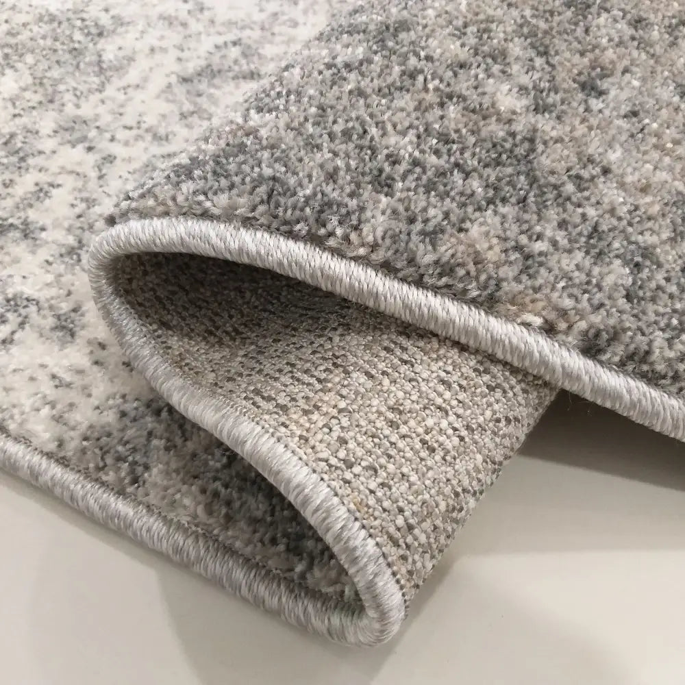 Modern Tepe Vista 05 grått teppe, nærbilde av brettet hjørne som viser strukturert veving og underside.