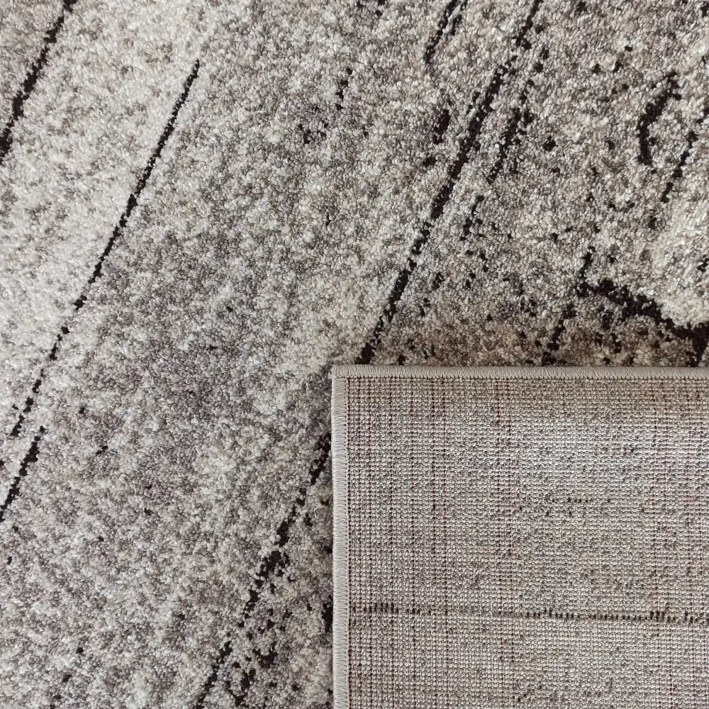 Tepe Panamero 20 teppe i grått og beige, abstrakt mønster, detalj av oppbrettet hjørne og synlig bakside.