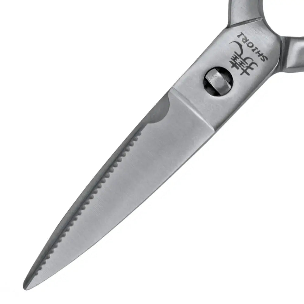 Multifunksjonell kjøkkensaks, nærbilde av det taggete stålbladet med gravert logo og synlig skruefeste.