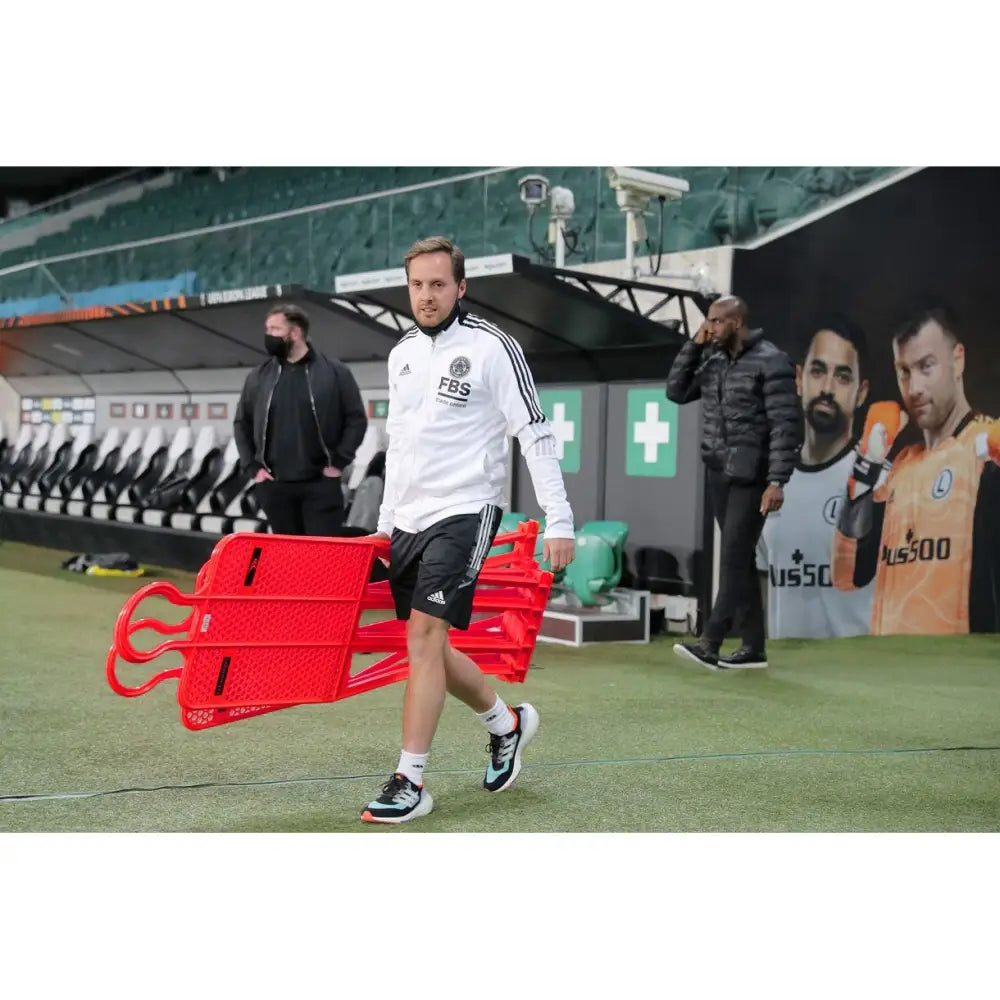 Mur Fotball PRO 180 cm, røde perforerte mannekenger bæres samlet av mann på fotballbane med tribuner.