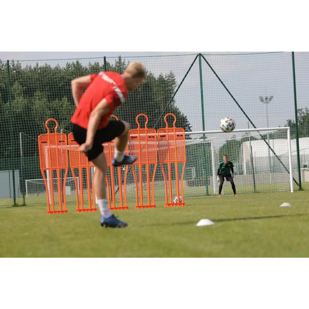 Mur Fotball PRO 180 cm, oransje treningsfigurer på bane mens spiller skyter mot mål med keeper i bakgrunnen.