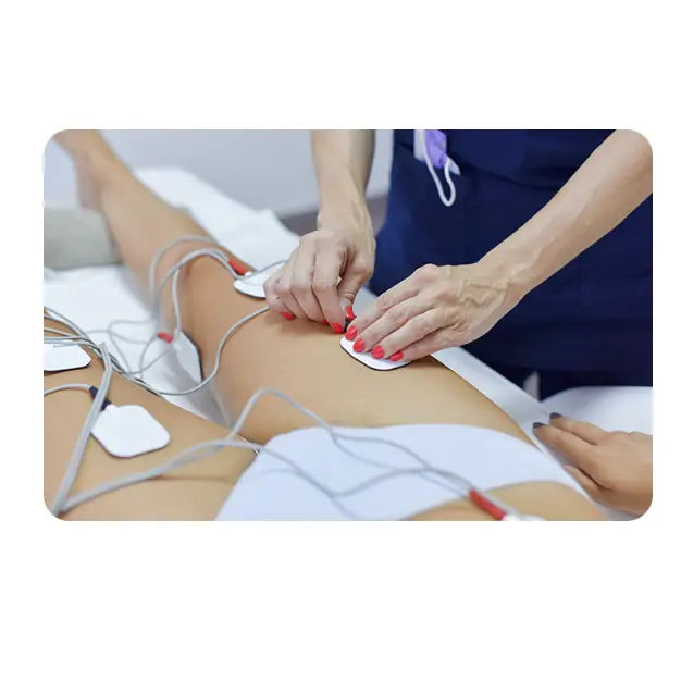 Muskelstimulator i bruk, nærbilde av elektrodepads festet på lår og hofte med tilkoblede ledninger.