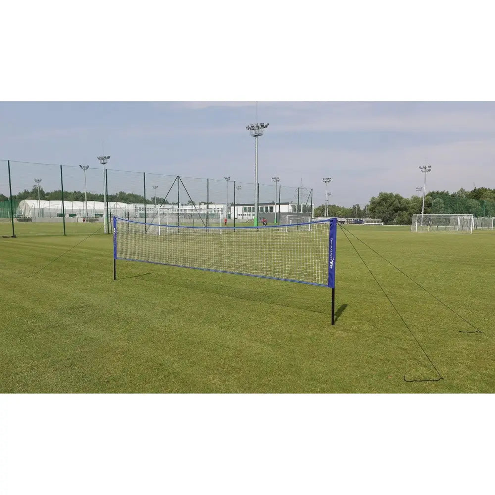 Naturlig gressmatte sett, utendørs nett med blå kant og sorte stolper festet på grønn plen med strammetau.