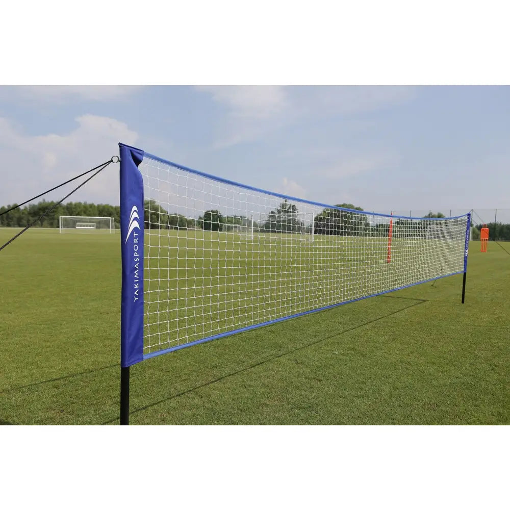 Naturlig gressmatte sett, sidevisning av hvitt nett med blå kanter og logo, montert på grønn gressbane.