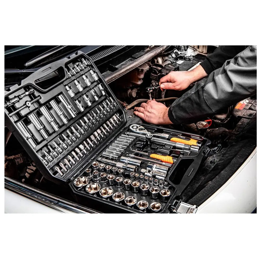 Neo Tools pipesett koffert, åpen ved bilmotor, viser bruk med ulike piper og verktøy i arbeidssituasjon.