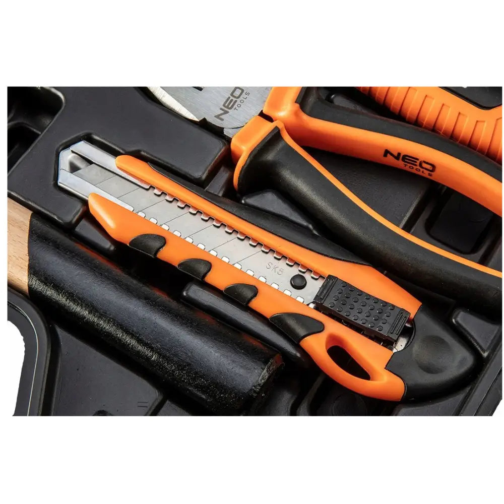 Tapetkniv med metallblad og oransje-svart håndtak, plassert blant andre verktøy i Neo verktøysett.