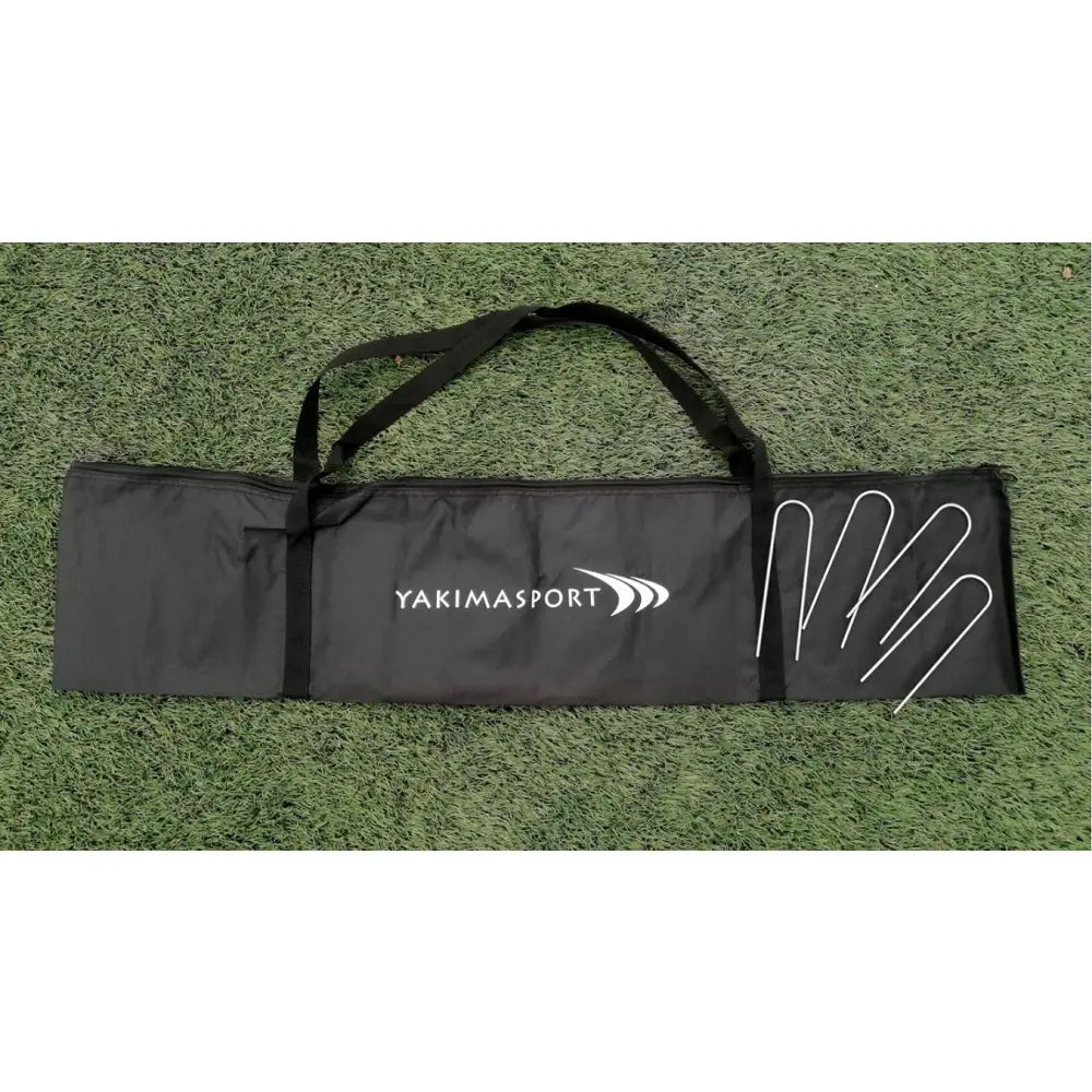 Nett for strandvolleyball, svart bag med Yakimasport-logo og fire metallpinner synlige på kunstgress.