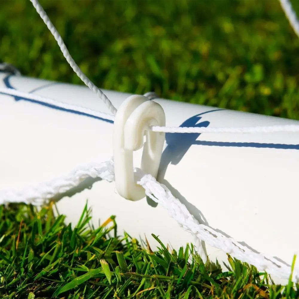 Nettbrettholder for fotball, nærbilde av hvit plastkrok i tau ved hvit stang på gress.