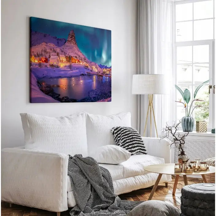Lerretsbilde med norsk vinterlandskap og nordlys på vegg i stilren stue med lyse tekstiler.