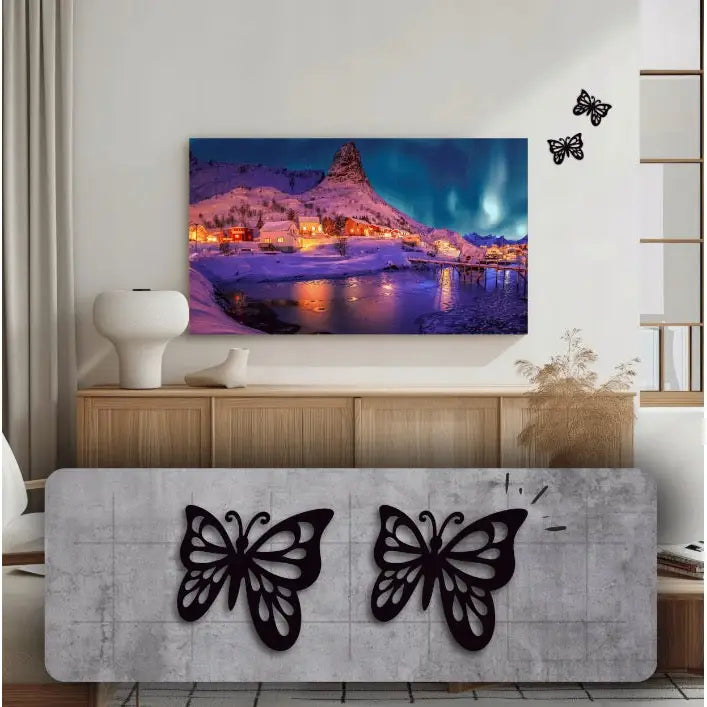 To sorte metall-butterfly montert på lys vegg over tregulv, ved siden av naturmotiv og minimalistisk interiør.