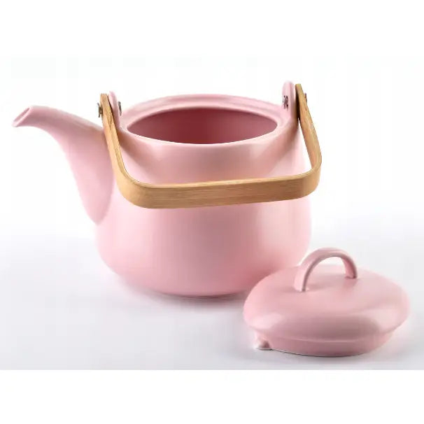 Pastellrosa tekanne i keramikk, sidevisning med lokket plassert ved siden av og lyst trehåndtak.