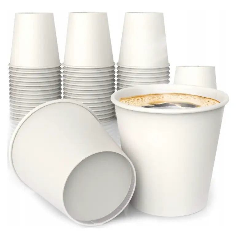 Øko hvite papirkopper for kaffe, ett fylt med skum, flere stablet og et tomt krus liggende foran.