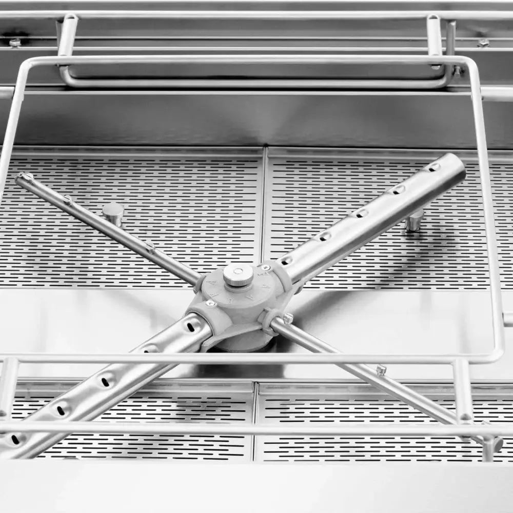 Industriell oppvaskmaskin, nærbilde av roterende spylearm i børstet stål med perforert rist og stålrør.