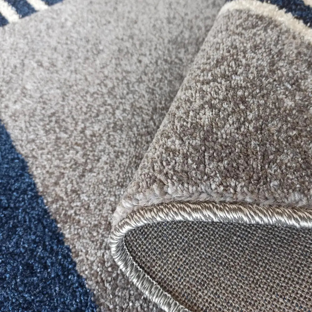 Otto Moderne teppe 240 x 330 cm, nærbilde av brettet hjørne med grå-blå farger, synlig underside og kant.