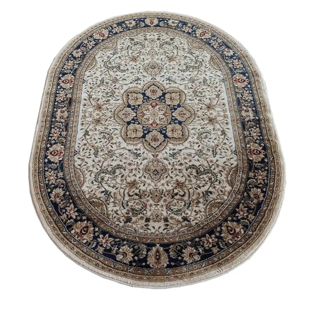 Ovalt teppe med orientalsk mønster i beige, blå og brunt, sett ovenfra med dekorative border og blomstermotiver.