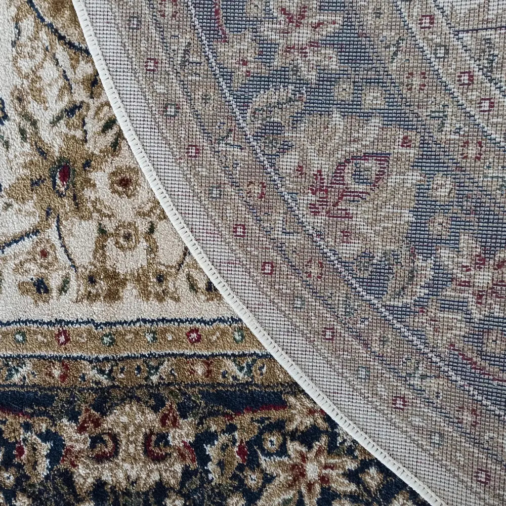 Ovalt eksklusivt teppe, nærbilde av hjørne med orientalsk mønster i beige, blått og rødt samt detaljert kanting.