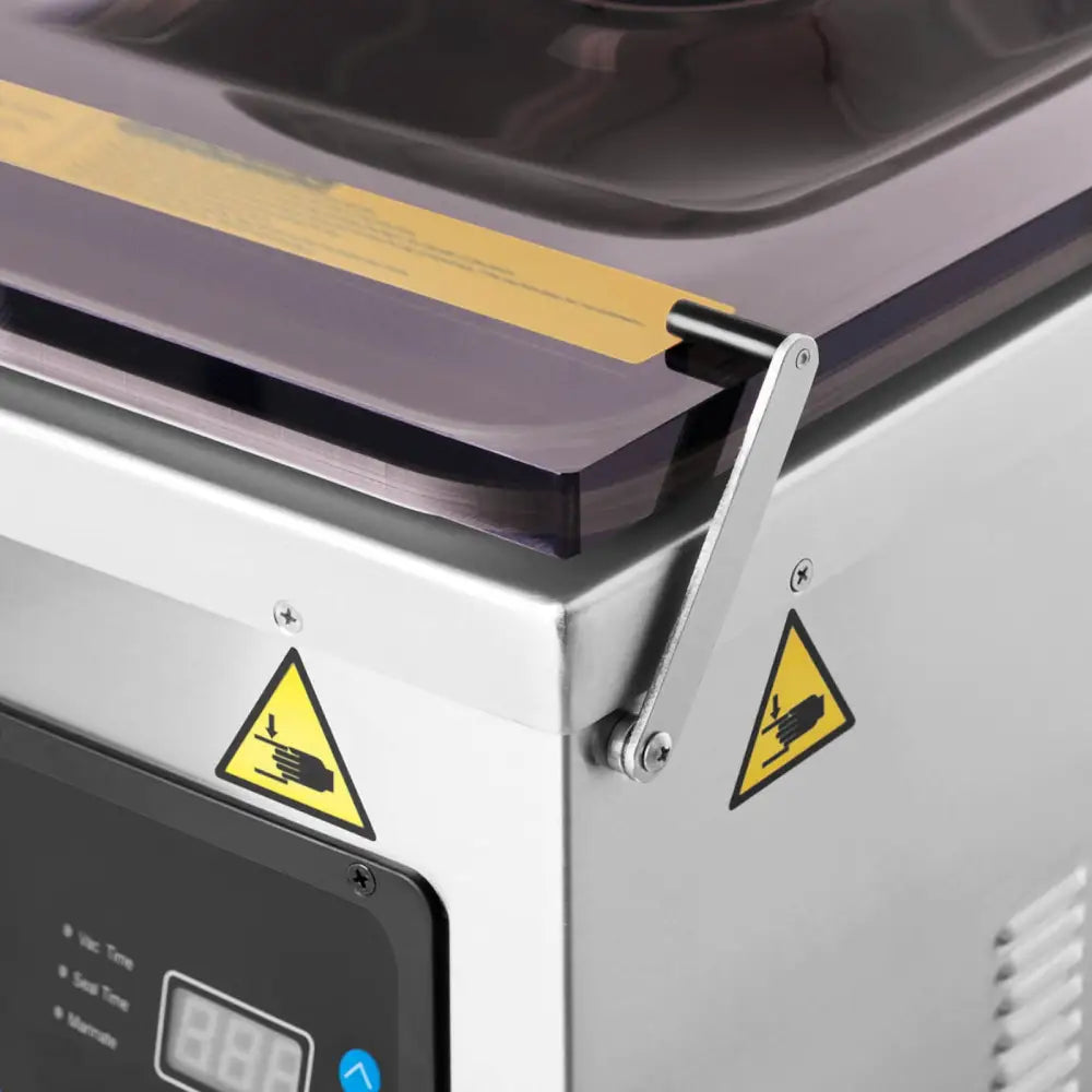 Pakker vakuum kammermatforseglingsmaskin, nærbilde av lokk, advarselsmerker og digitalt display i stålfinish.