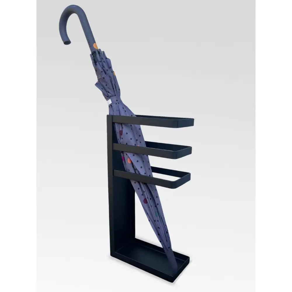 Paraplystativ i svart metall med minimalistisk design, inneholder blå paraply med fargerike prikker.