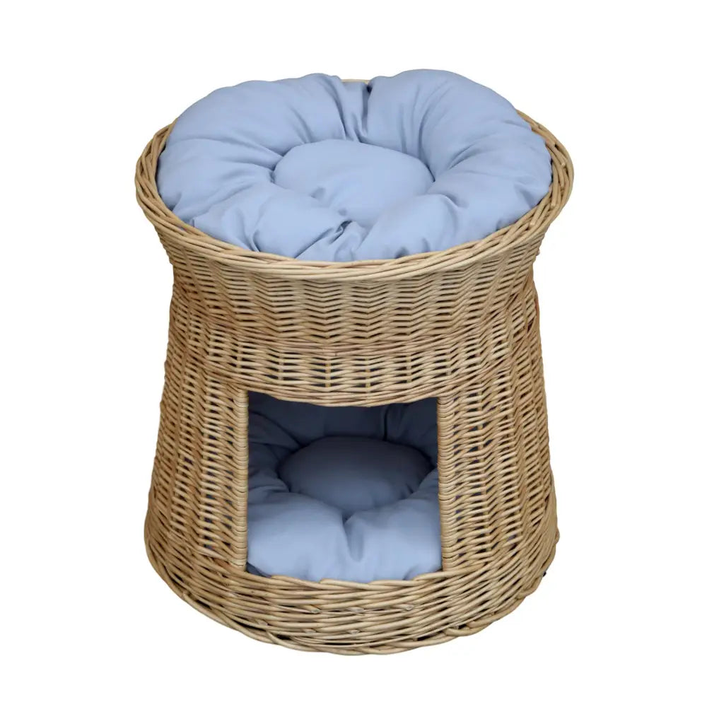Pilhytte i kurv med rund åpning, blå polstrede puter på topp og inni, sett forfra mot hvit bakgrunn.