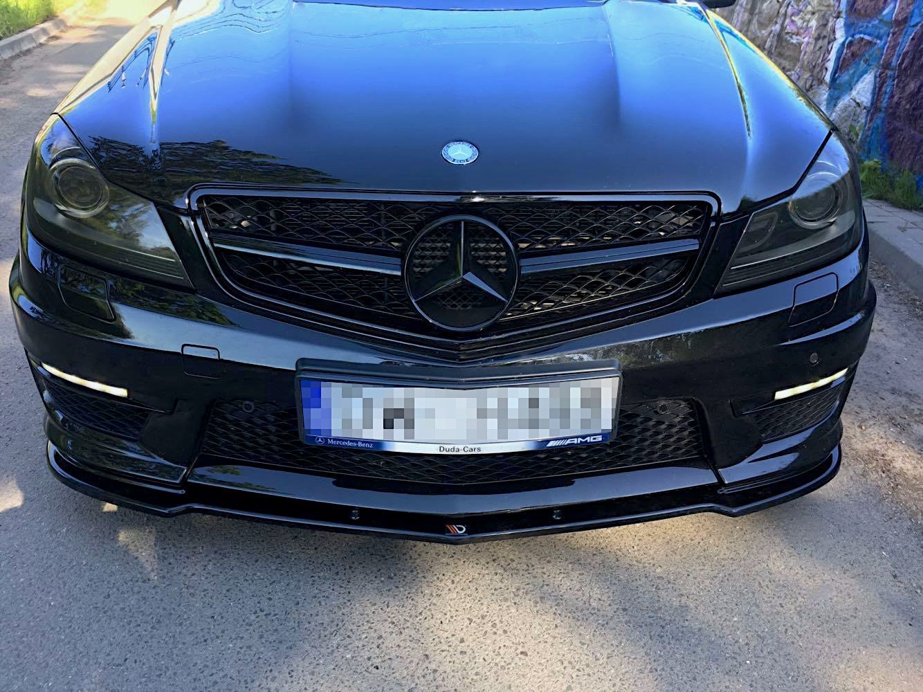 Frontspoiler til Mercedes C63 AMG W204 Facelift, sort med store luftinntak og AMG-merke, sett forfra.