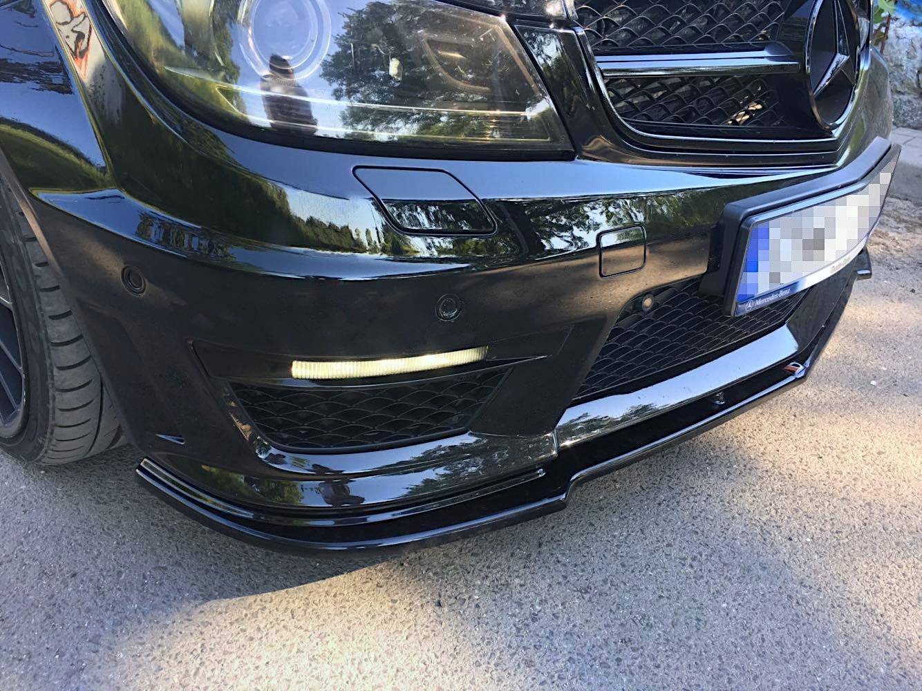Frontleppe til Mercedes C63 AMG med sportsgitter, LED-lys og skinnende sort finish sett fra skrå vinkel.