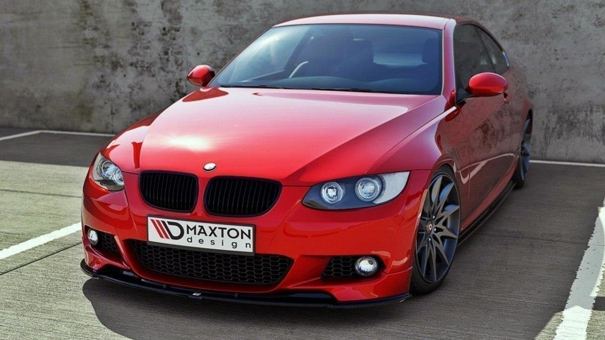 Frontspoiler BMW 3 E92 M-Pakke på rød sportsbil med sorte detaljer og lav frontleppe, parkert mot betongvegg.