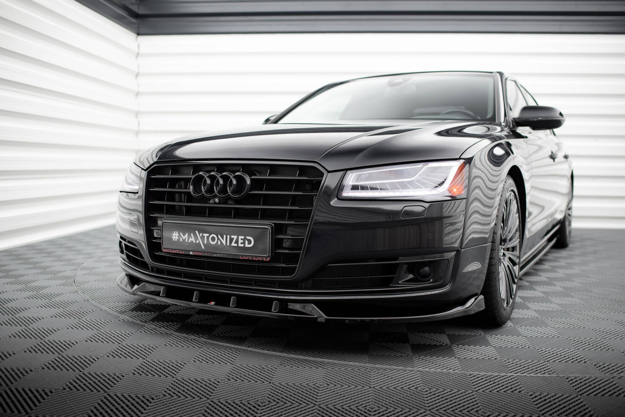 Frontspoiler Audi A8 D4 Facelift sort bil med LED-frontlykter og grill sett forfra i lyst rom.