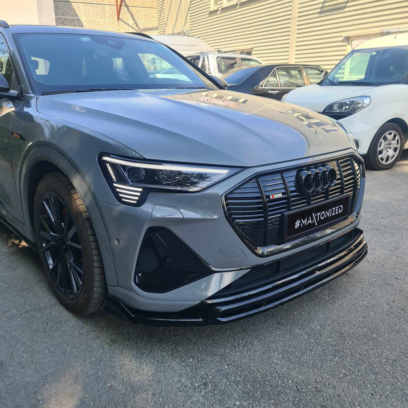 Frontleppe på Audi E-Tron S-Line med sort grill, LED-frontlykter og sorte felger sett skrått forfra.