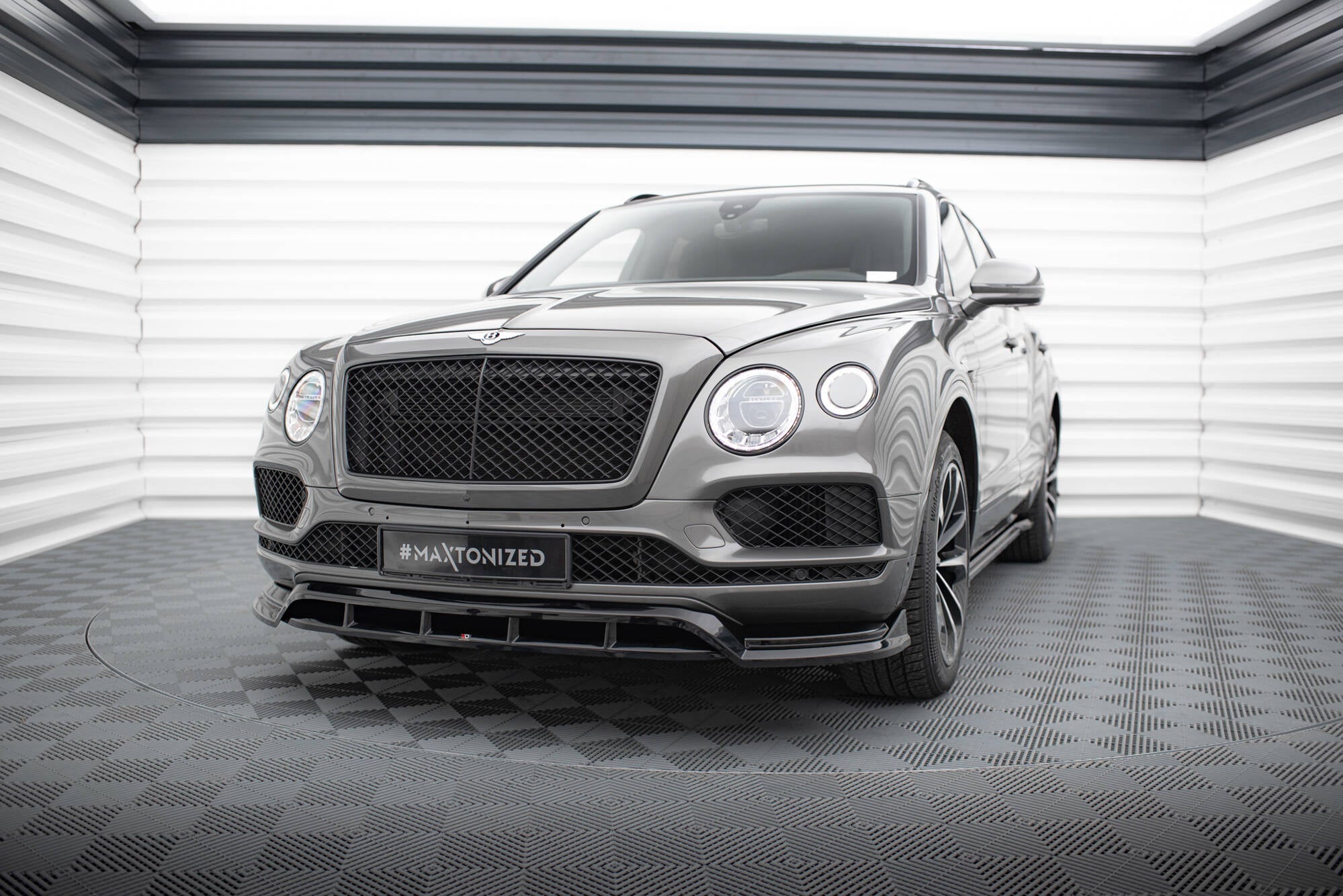 Frontspoiler Bentley Bentayga MK1 SUV med store sorte felger og markant frontgrill i lyst industrilokale.
