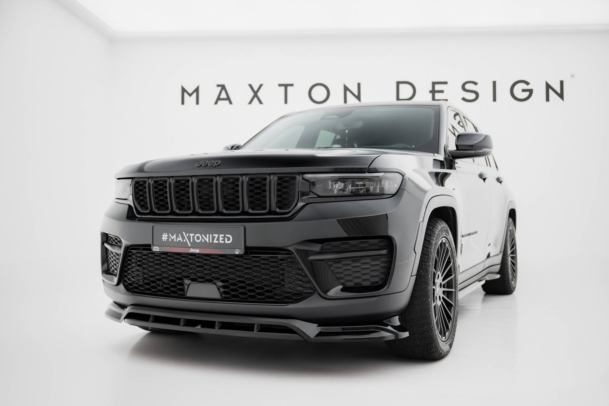 Frontspoiler på Jeep Grand Cherokee Trailhawk MK5, svart SUV med sporty spoiler og store felger i lyst studio.