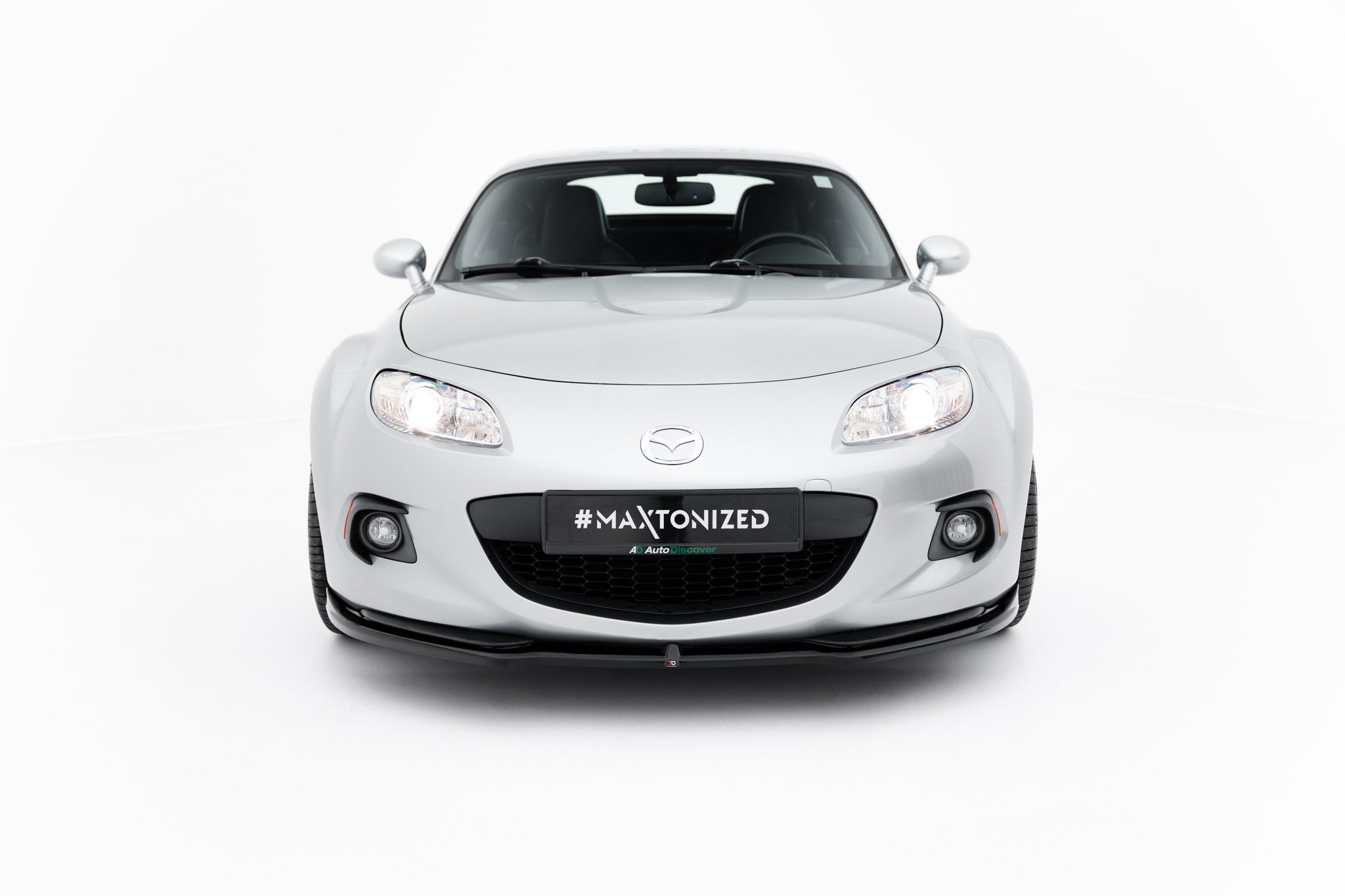 Spoiler på Mazda Mx-5 MK3 Facelift, sølvfarget bil forfra med sorte detaljer og tent frontlys.
