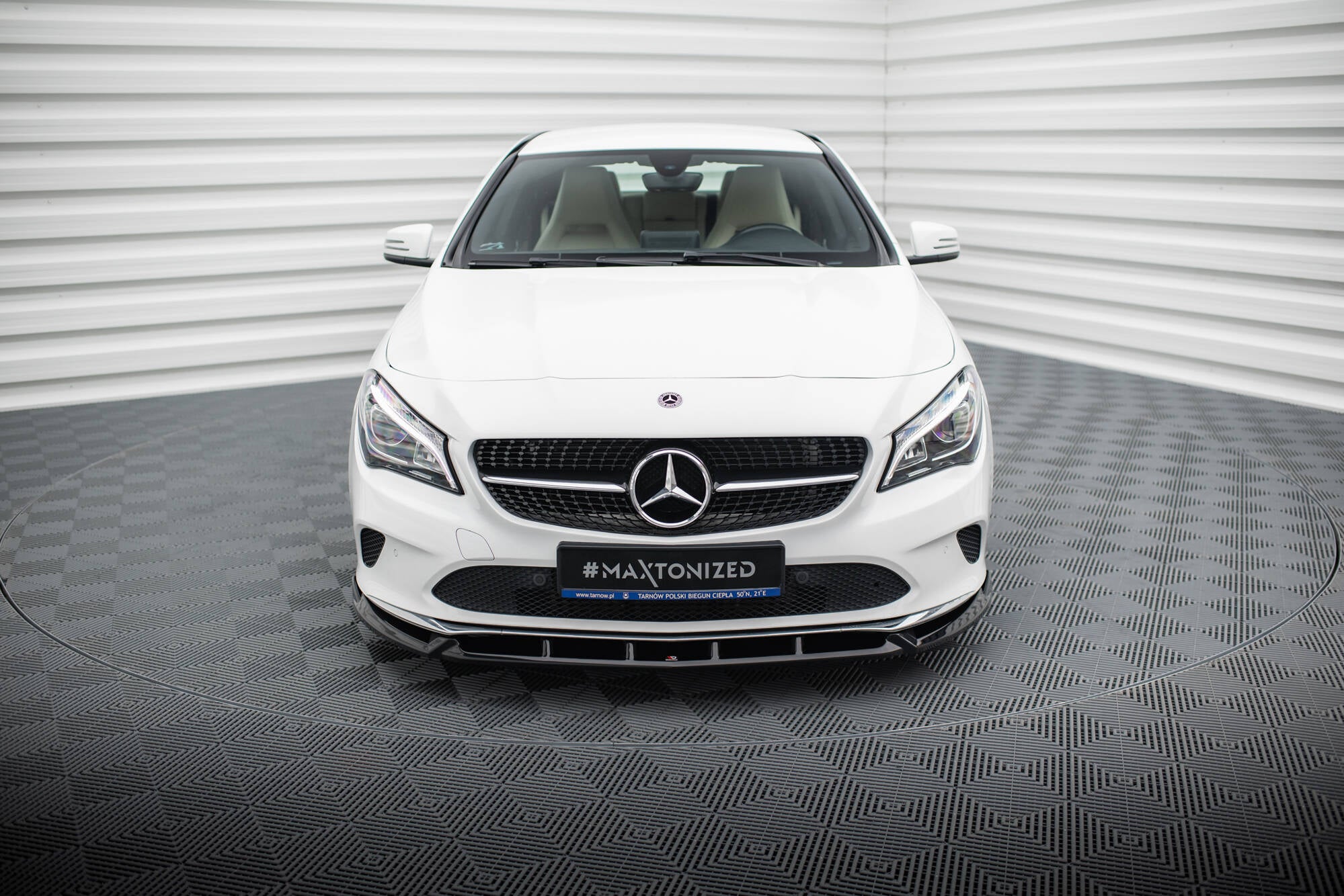 Frontleppe på Mercedes CLA C117 Facelift med sort grill og LED-frontlykter, sett forfra i fotostudio.