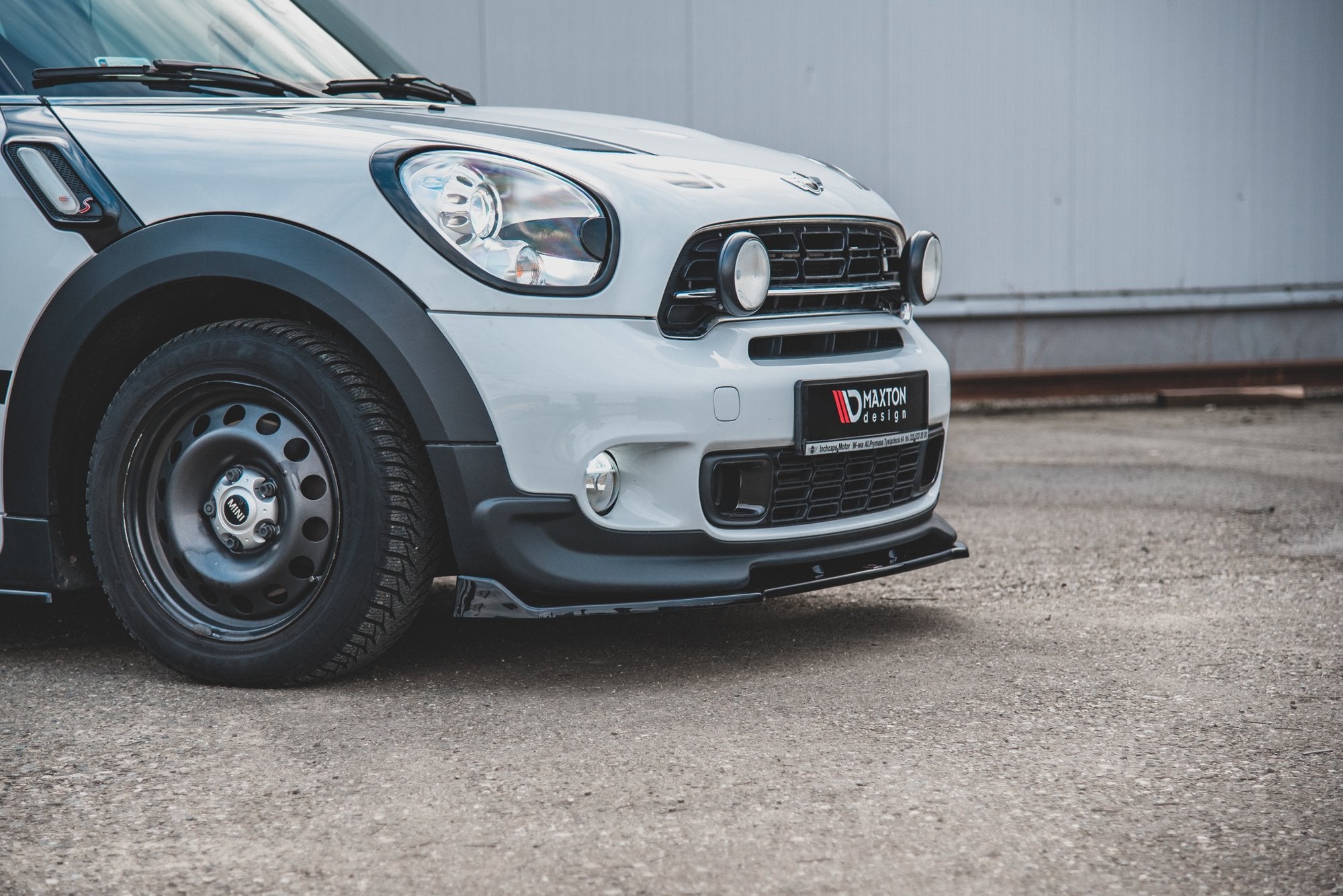 Frontleppe Mini Countryman MK1 Jcw med sorte detaljer, ekstralys og stålfelg på hvit bil.