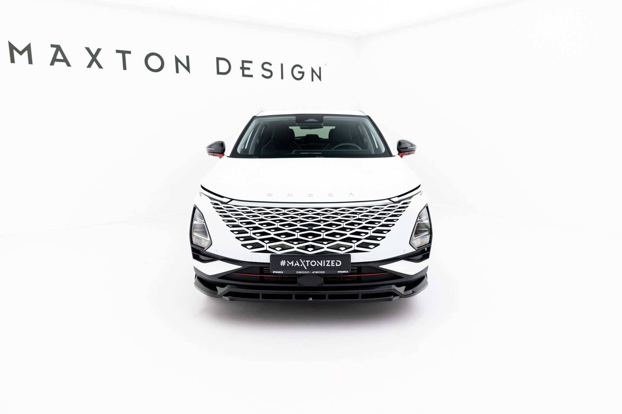 Front splitter på Omoda 5 MK1, hvit bil forfra med diamantgrill og smale lykter i lyst studio.