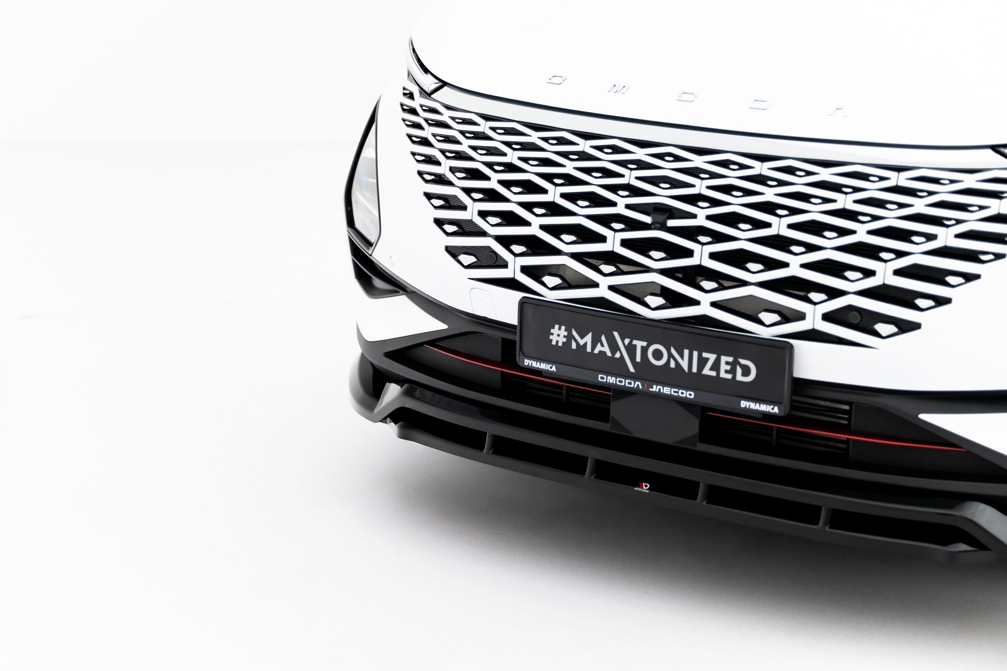 Front lip på Omoda 5 MK1, nærbilde av hvit bil med sort og sølv geometrisk grill.
