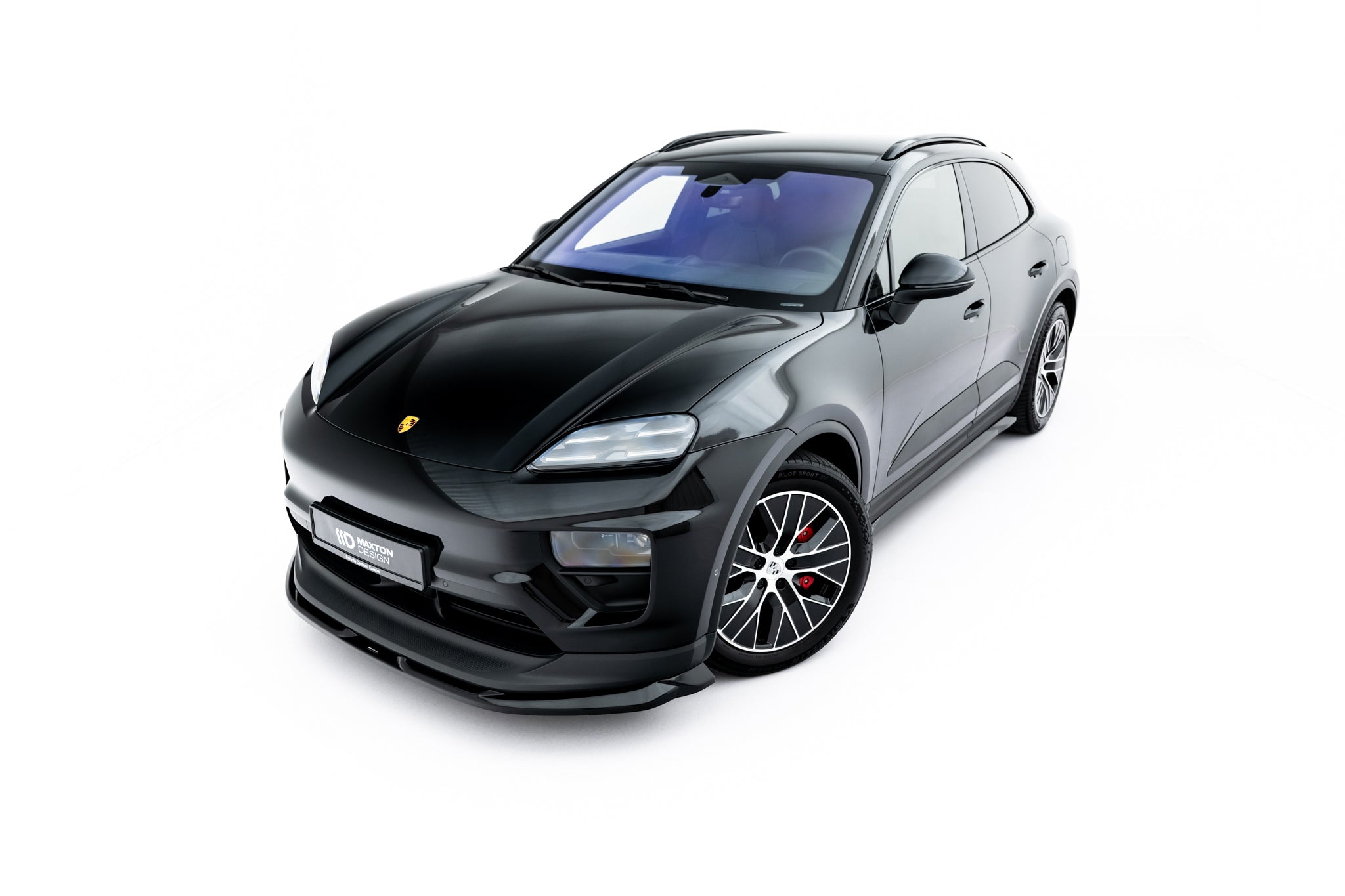 Front splitter på Porsche Macan Ev MK1, svart SUV med rød bremsekaliper og sportslig frontspoiler.