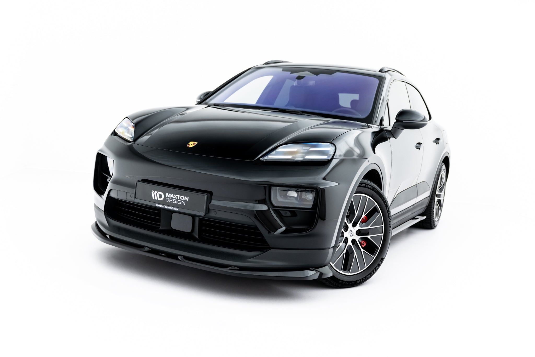 Frontspoiler på Porsche Macan Ev MK1 svart SUV med store felger og røde bremsekalipere.
