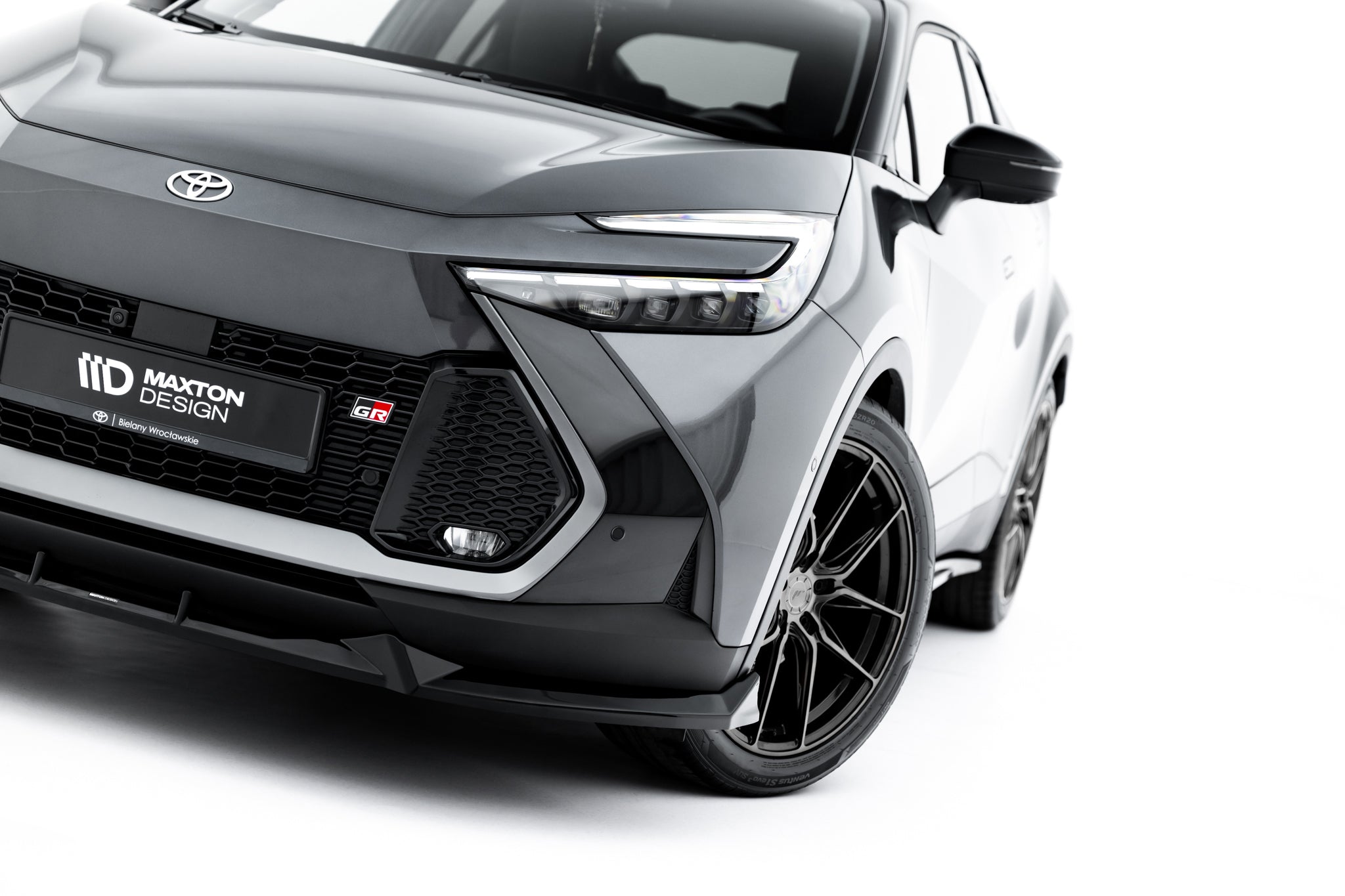 Front lip på Toyota C-Hr MK2 med markante LED-lykter, sort grill og GR-emblem, sett fra skrå vinkel.