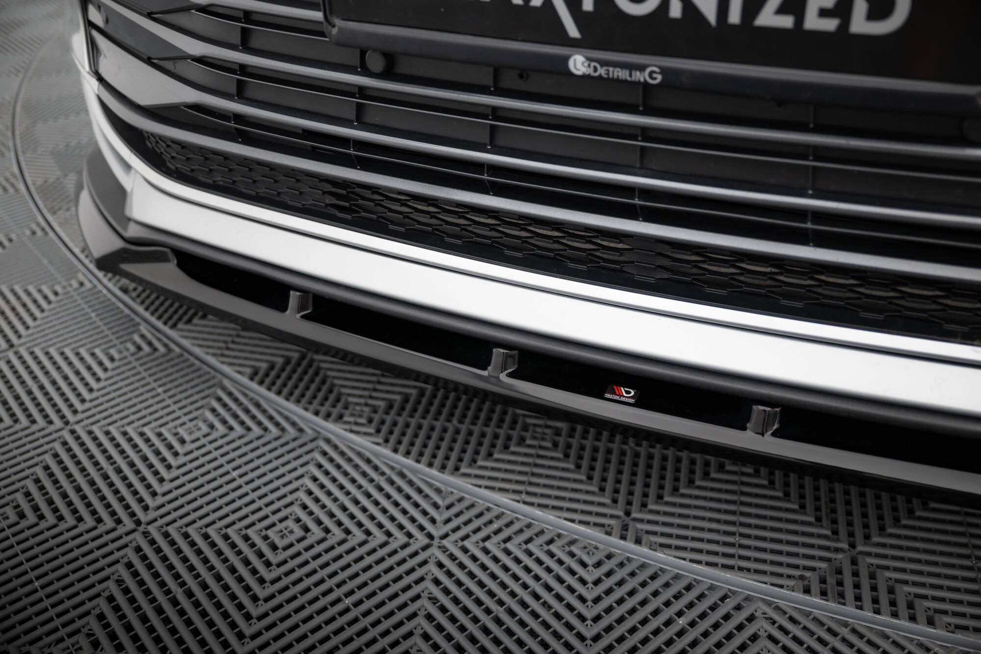 Spoiler til Toyota Sienna MK4 i blank svart finish, nærbilde med synlig logo og mønstret gulv i bakgrunnen.