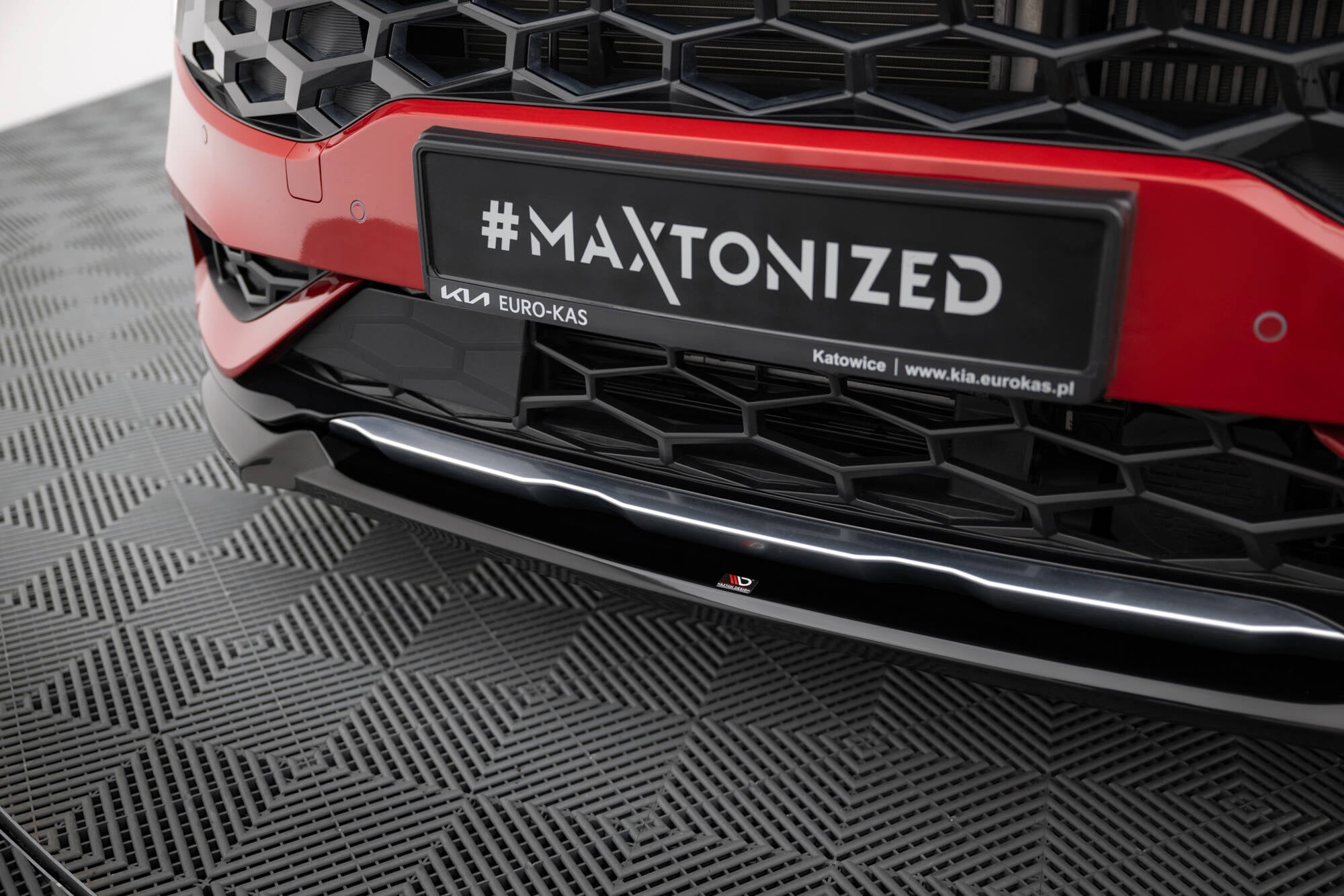 Spoiler Kia Sportage GT-Line MK5 i sort blank plast med rød detalj og bikubemønstret grill.