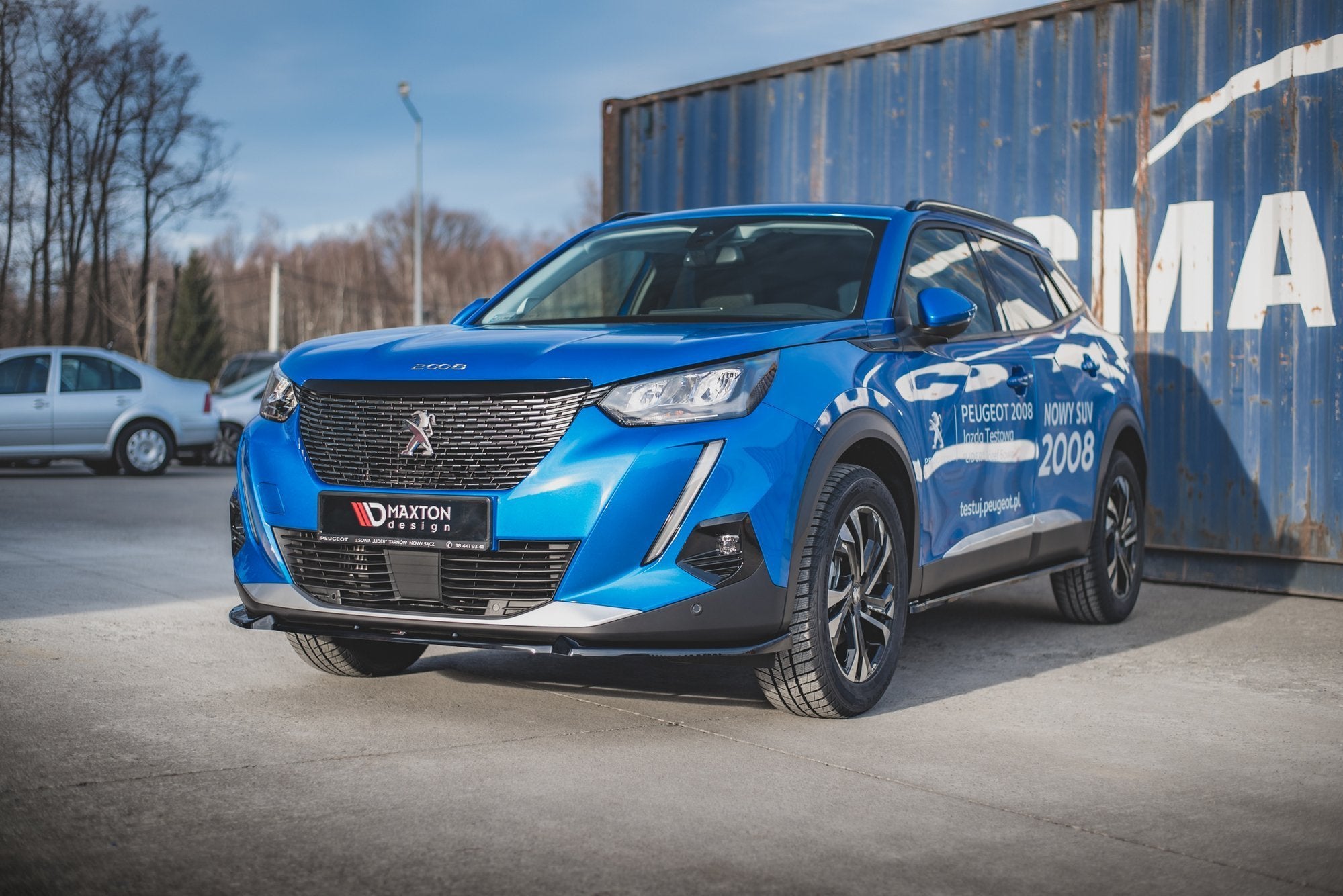 Front splitter på Peugeot 2008 MK2 V.1, blå SUV med svarte detaljer foran blå container.