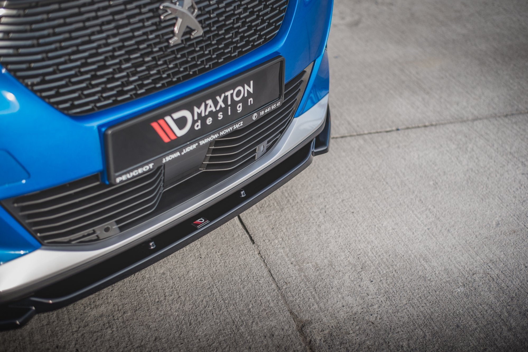 Spoiler til Peugeot 2008 MK2 V.2 i sort plast med sølvdetaljer, montert på blå bil nær bakken.