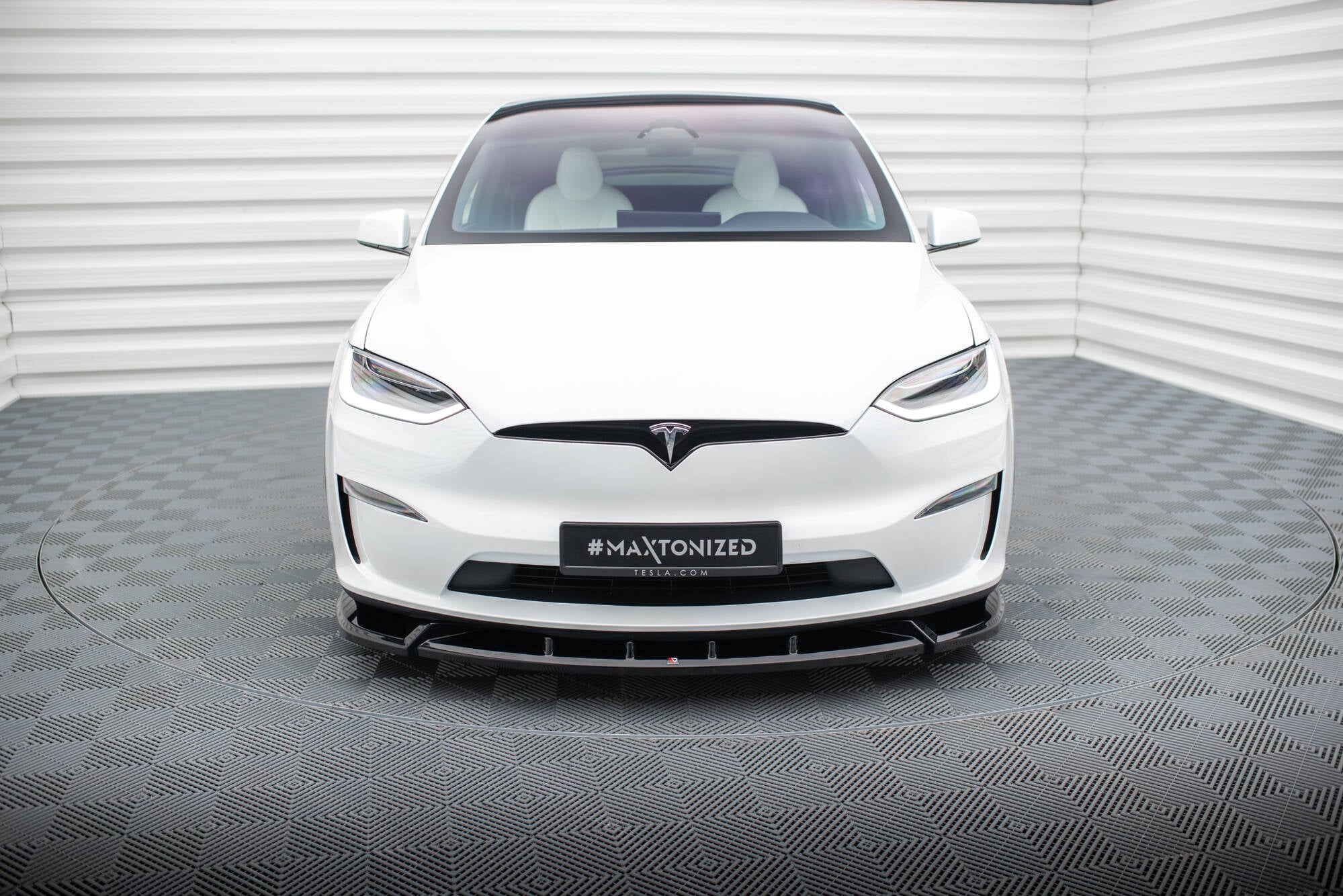 Frontleppe på hvit Tesla Model X MK1 Facelift V.2 med svart frontsplitter, sett forfra i lyst studio.