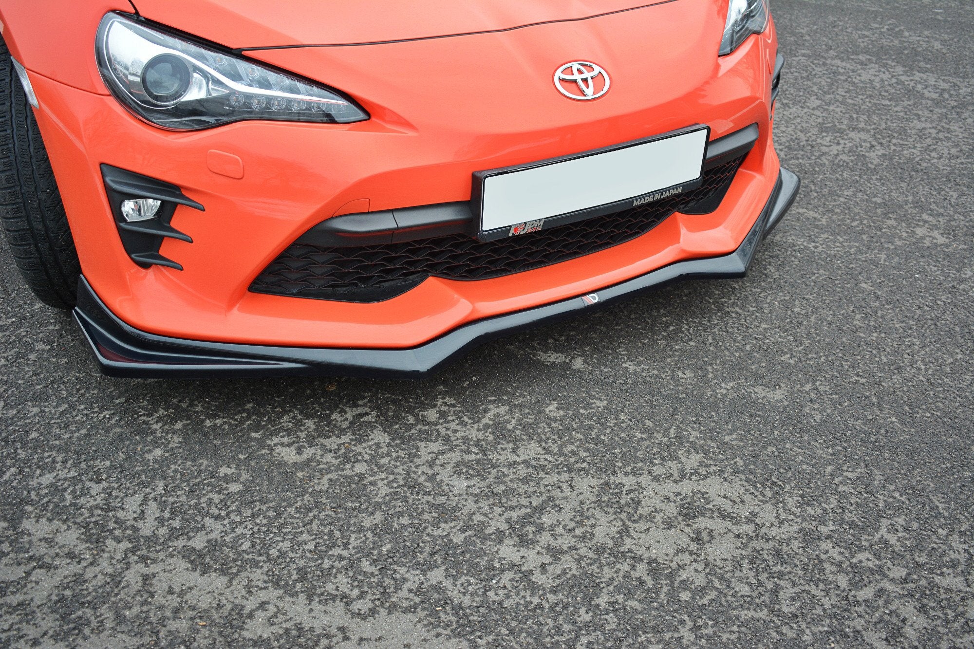 Spoiler på Toyota GT86 Facelift V.2, nærbilde av sort frontsplitter med grill og tåkelys på oransje bil.