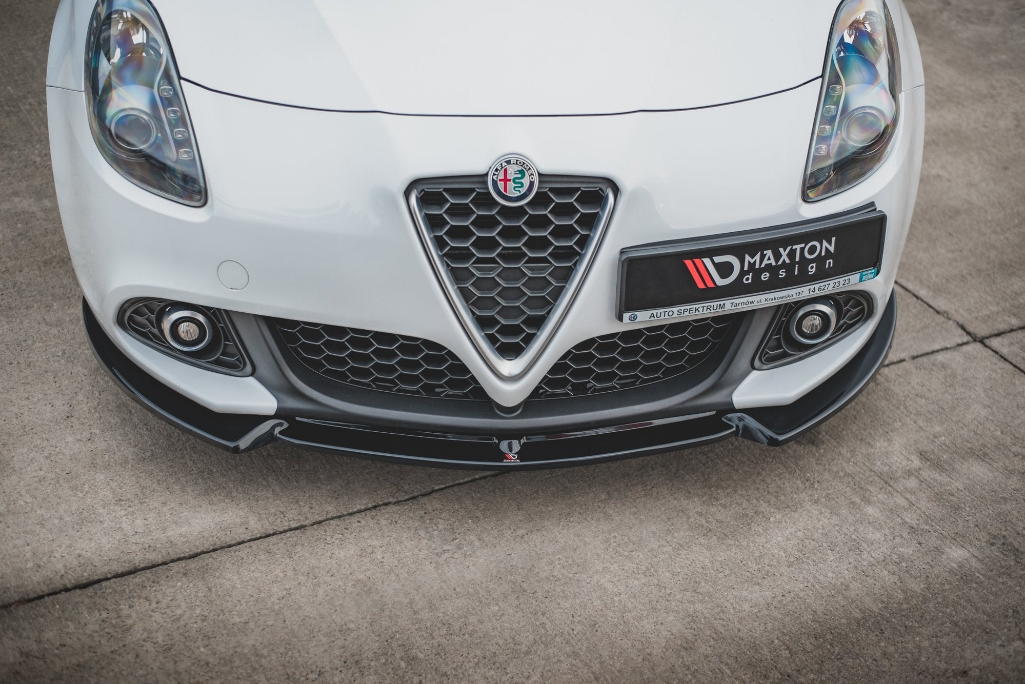 Front splitter til Alfa Romeo Giulietta V.3 montert på hvit bil med sort grill og tåkelys.