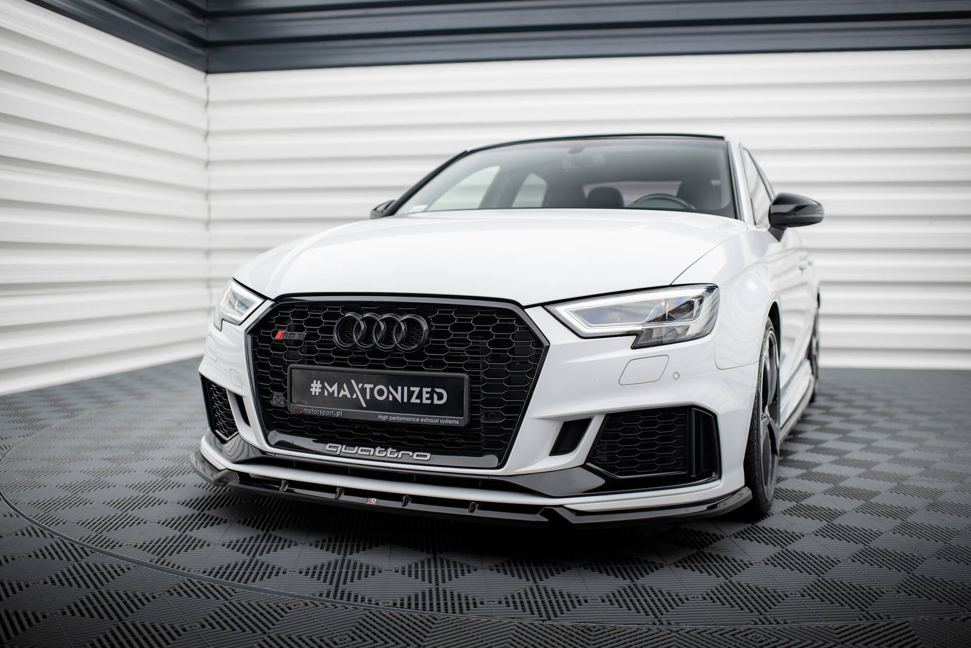 Frontspoiler Audi RS3 Sedan 8V Facelift V.3 montert på hvit bil med sort grill i lyst industrilokale.