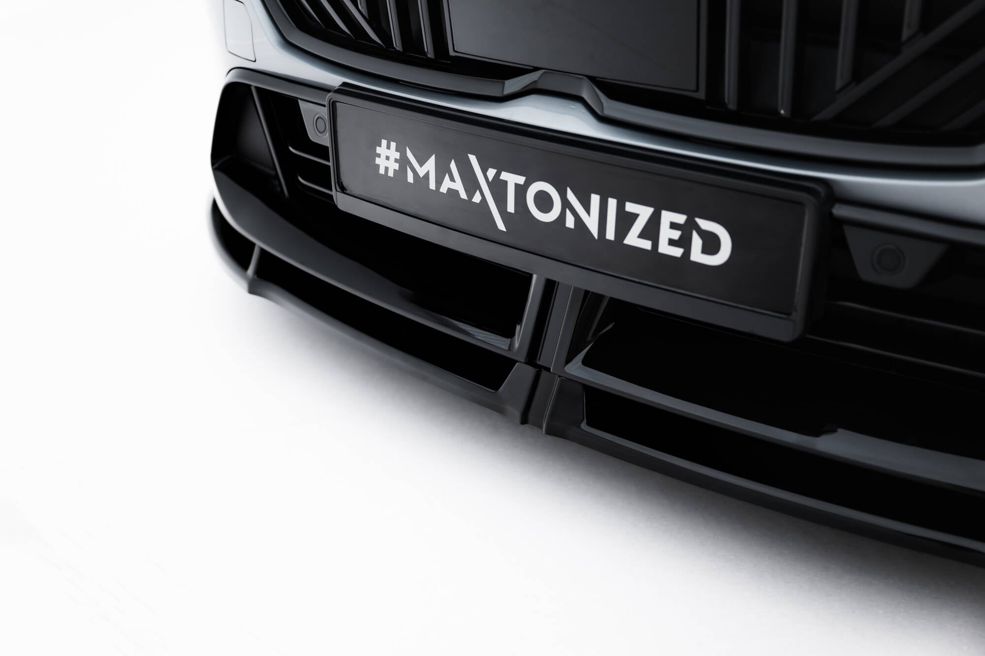Spoiler til BMW F70 M135I V.3 i sort glanset plast, nærbilde montert under grill med #MAXTONIZED-skilt.
