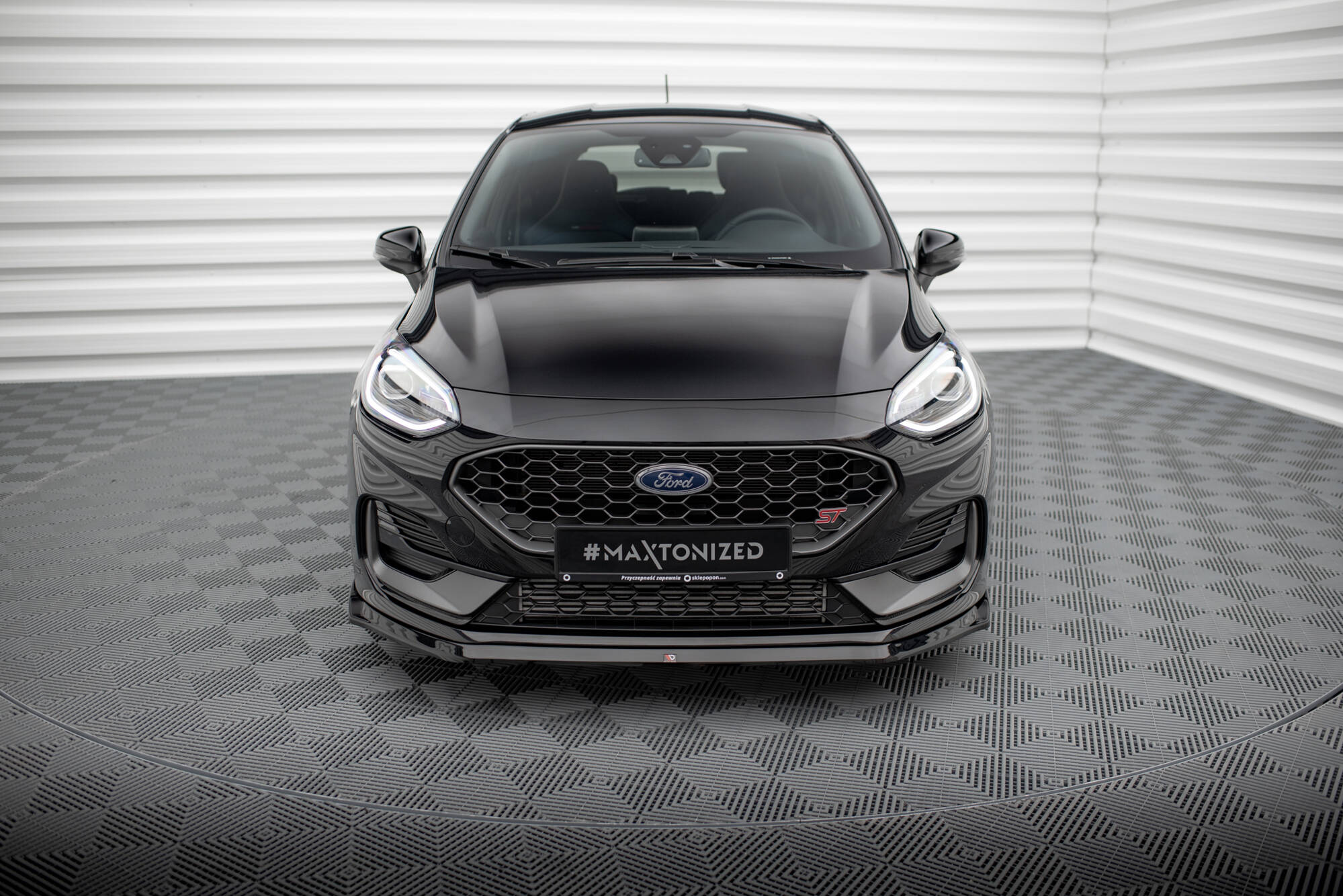 Frontleppe til Ford Fiesta MK8 Facelift vises montert på svart bil med LED-lys og bikubemønstret grill.
