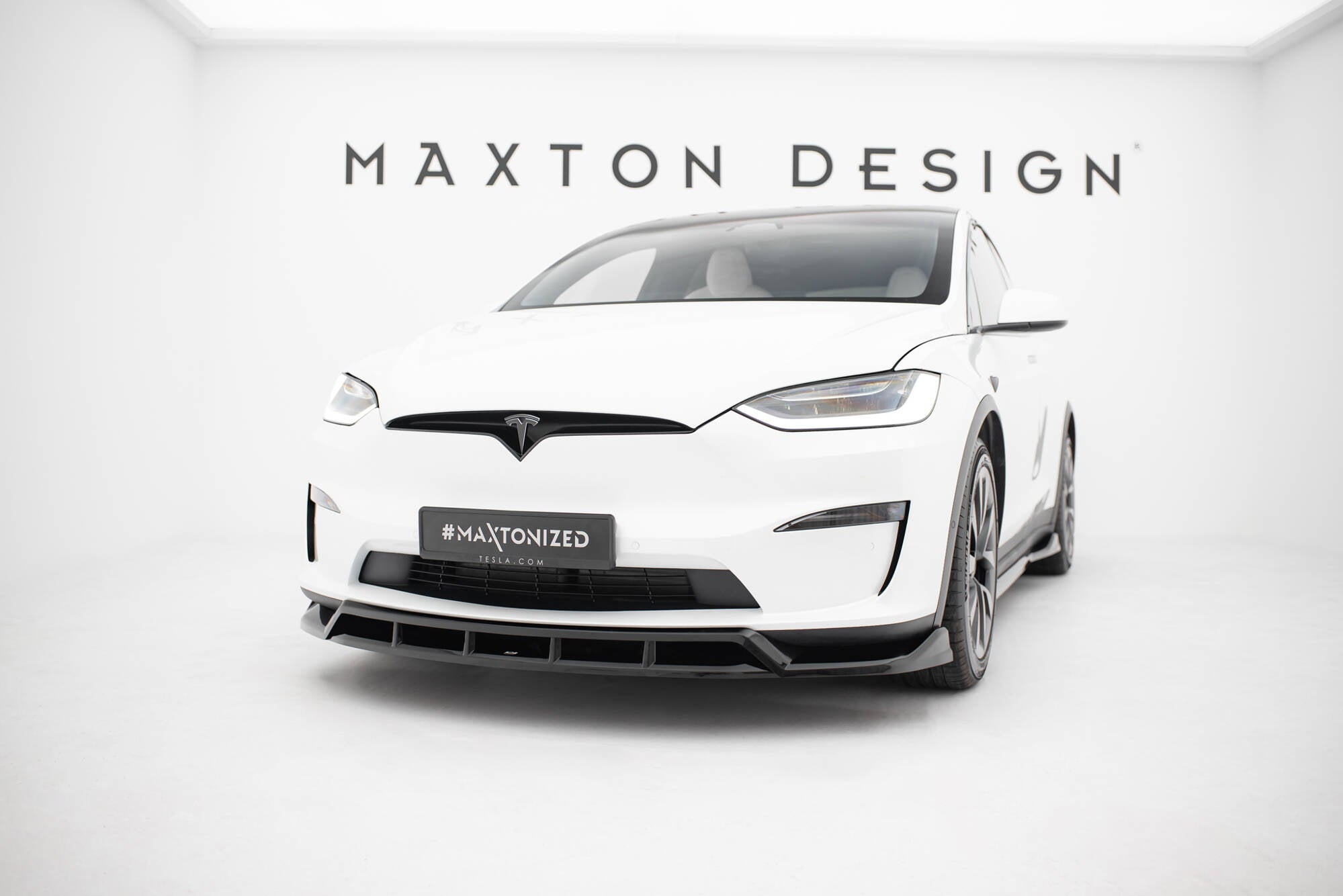 Frontspoiler til Tesla Model X MK1 Facelift V.3 montert på hvit bil med sorte aerodynamiske detaljer.