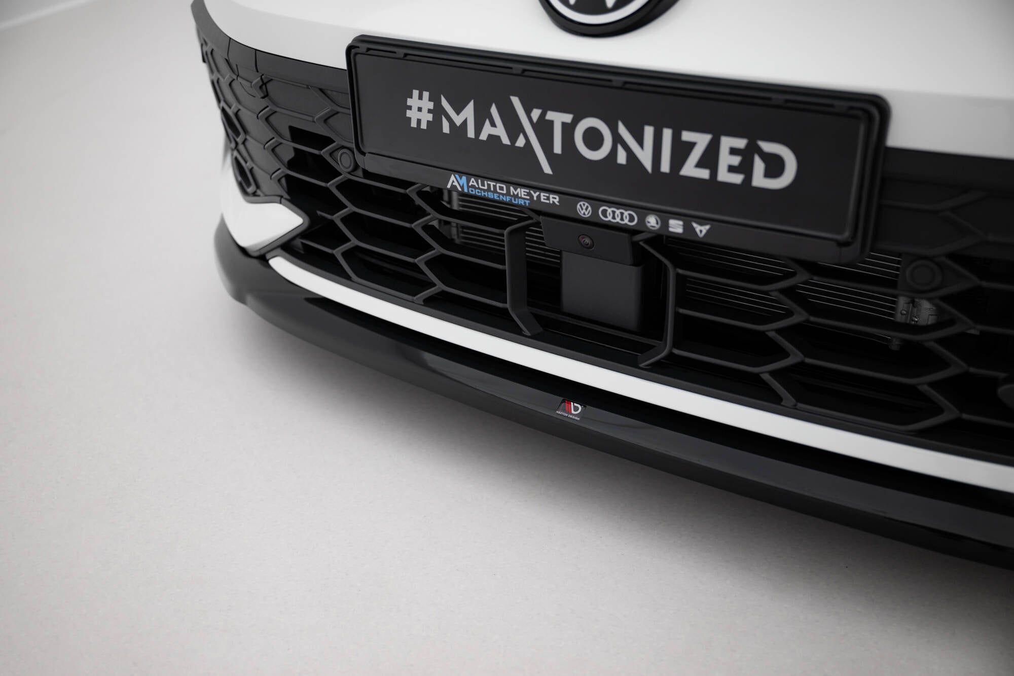 Spoiler til VW Golf MK8 Facelift GTI med svart og hvit front, Maxton-merke og #MAXTONIZED-skilt.